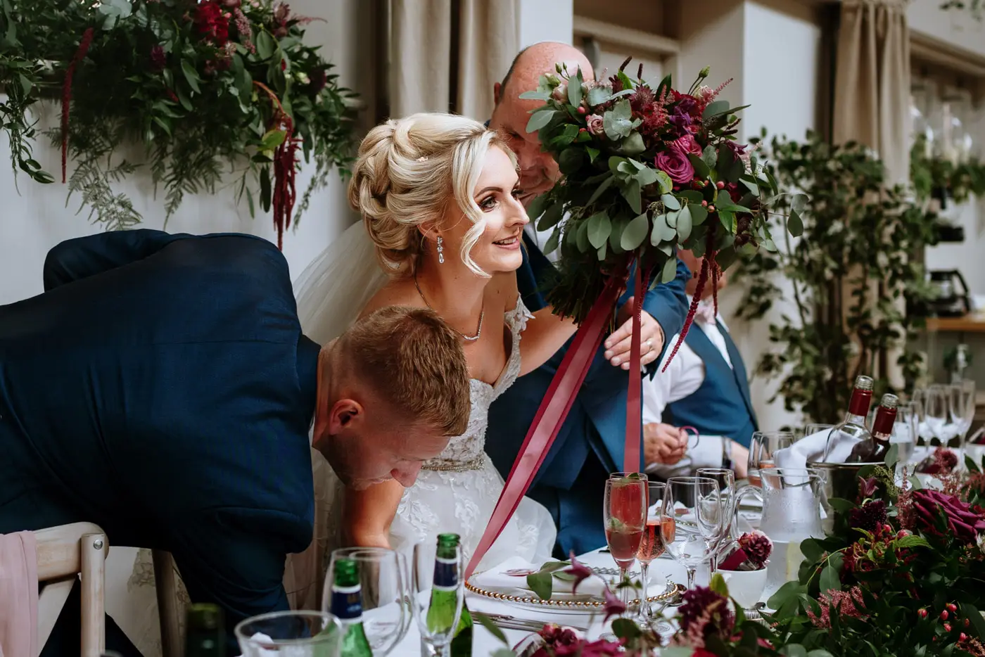 Bride Louise being seated at the wedding breakfast table by her father and her new husband Martin at Doddington Hall, Lincolnshire