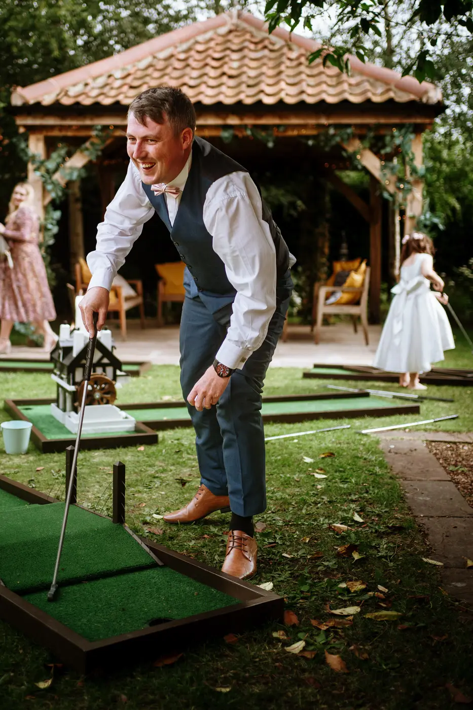 A guest playing the mini golf in the gardens at Doddington Hall and laughing his head off during Louise and Martin's wedding reception