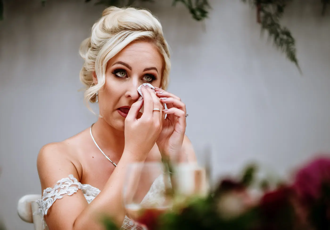 Bride Louise shedding a tear with emotion during the wedding speeches at Doddington Hall, Lincolnshire, captured by documentary photographer Gary Phillip