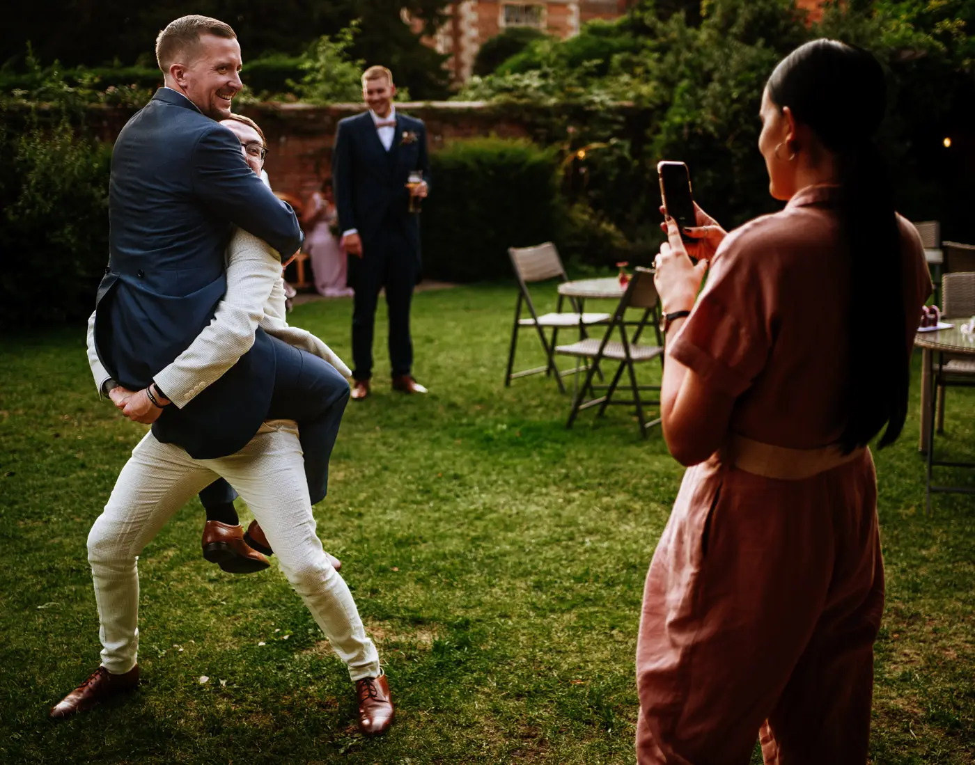 Guests larking around in the coach house garden at Doddington Hall after the wedding dinner, candid evening photography by Gary Phillip