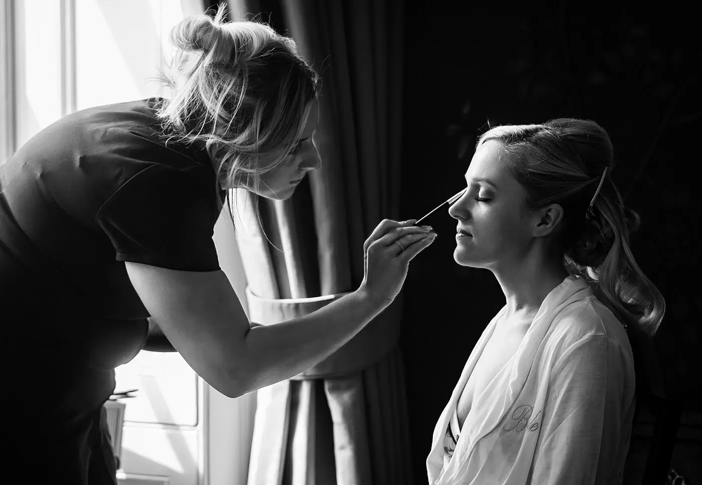 Bride Sally having her makeup applied by the makeup artist in beautiful natural light at Stubton Hall, Nottinghamshire, bridal preparation photography by Gary Phillip