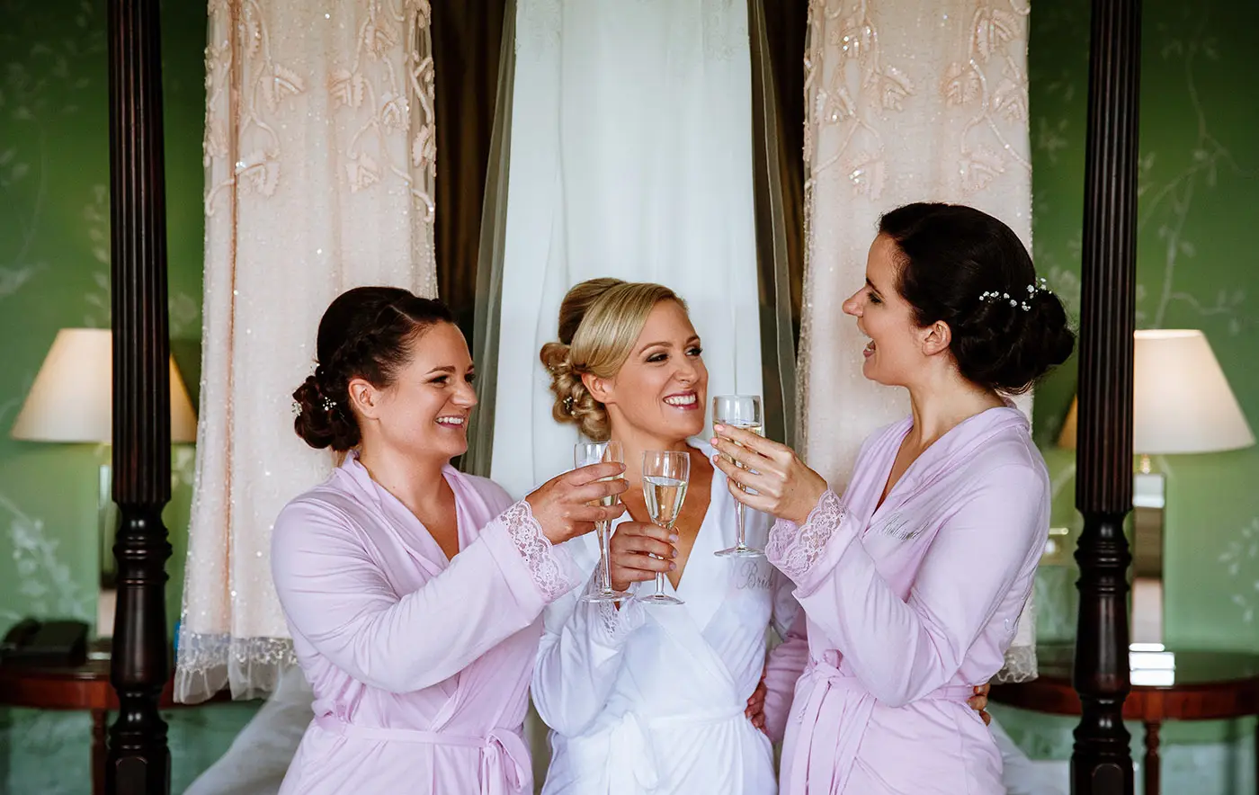 Bride Sally and her bridesmaids raising their glasses of fizz in a toast at Stubton Hall on her wedding morning, a joyful candid moment by Gary Phillip