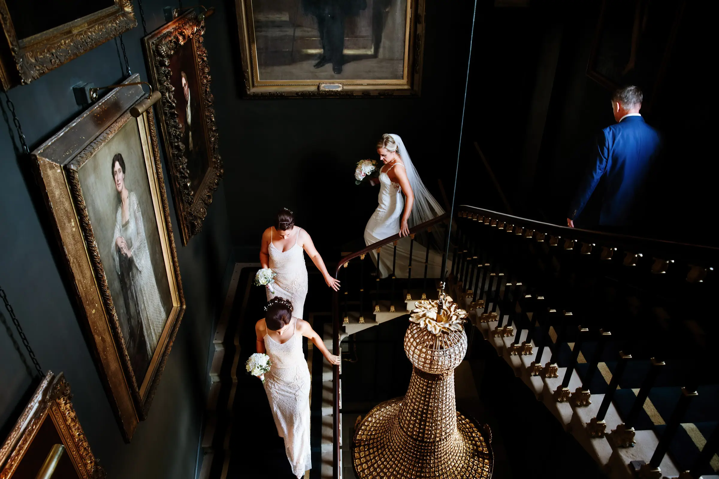 Bride Sally descending the grand staircase at Stubton Hall with her two bridesmaids and her father, a defining moment from her wedding day photographed by Gary Phillip