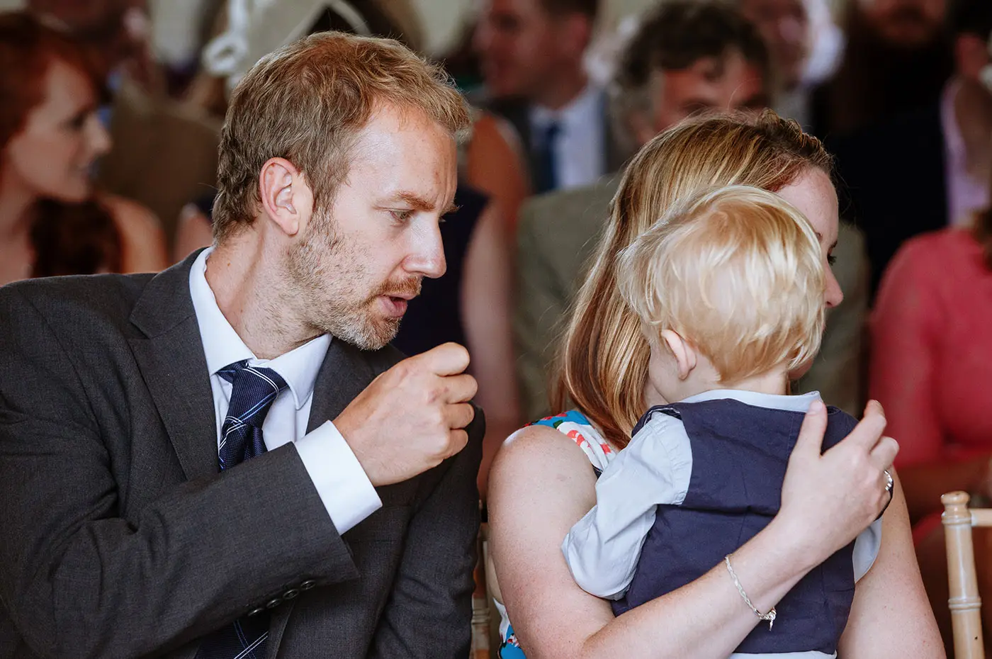 A guest waiting in the wedding room at Stubton Hall with his wife and baby son before the ceremony, a quiet family moment captured by Gary Phillip