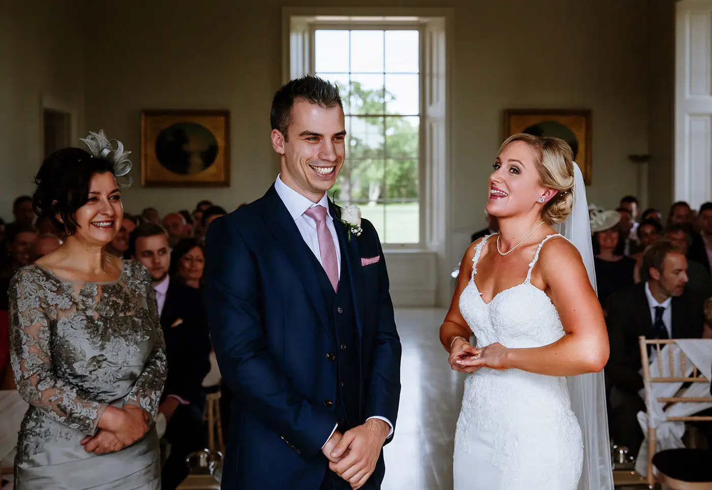 Bride Sally pushing her wedding ring on with her tongue stuck out as groom Luke struggles to get it all the way on during the ceremony at Stubton Hall, Nottinghamshire