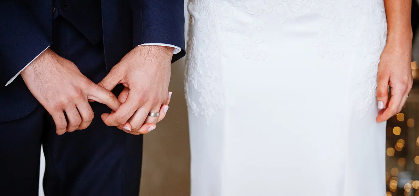 Groom Luke holding bride Sally's hand with both of his during their wedding ceremony at Stubton Hall, Nottinghamshire, an intimate hand detail by Gary Phillip