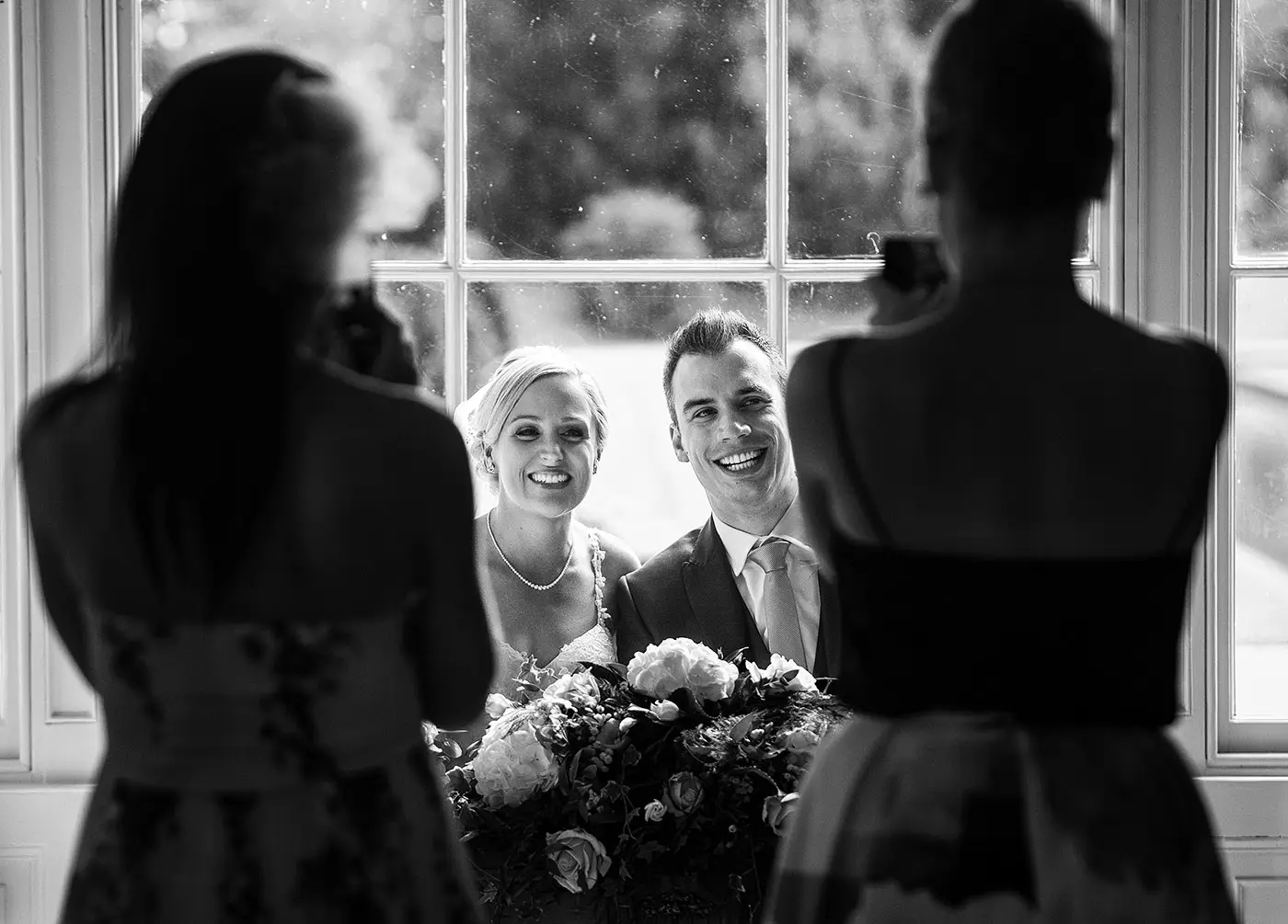 Bride Sally and groom Luke smiling for guest photographs after signing the wedding register at Stubton Hall, Nottinghamshire, documentary wedding photography by Gary Phillip