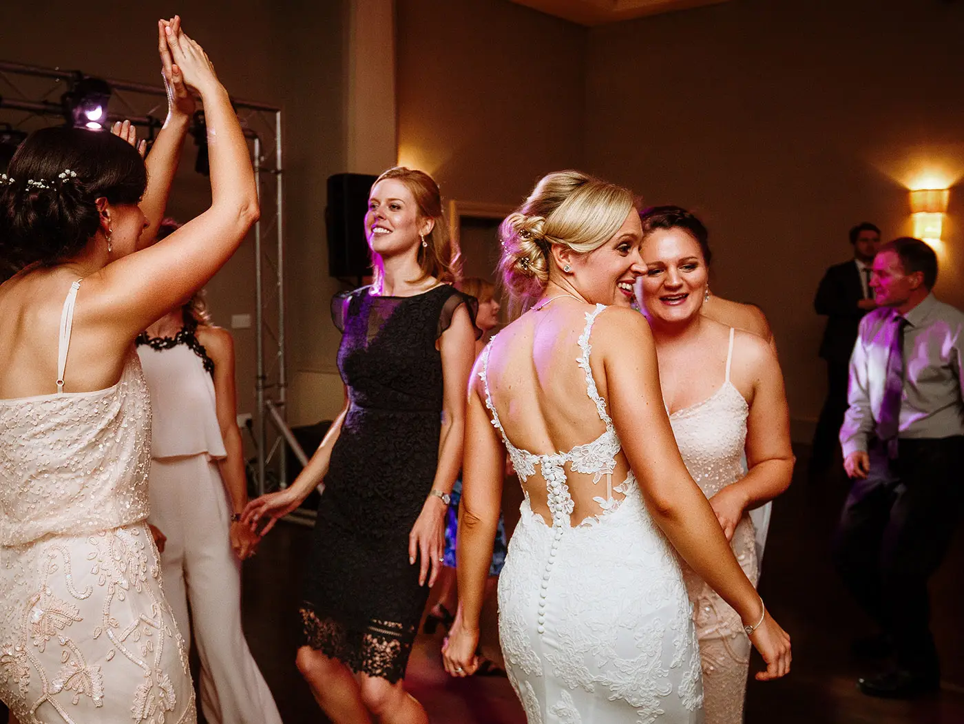 Bride Sally dancing joyfully with her bridesmaids on the dancefloor at Stubton Hall, Nottinghamshire, candid evening wedding photography by Gary Phillip