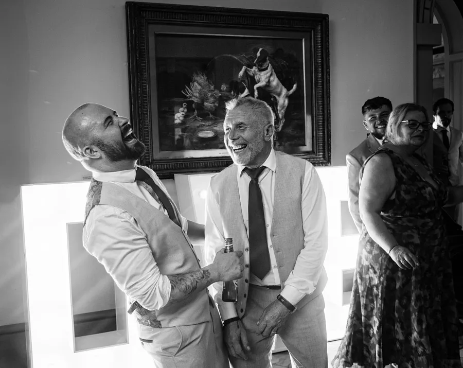 Groom laughing with a guest in the reception rooms at Wollaton Hall — wedding photography by Gary Phillip