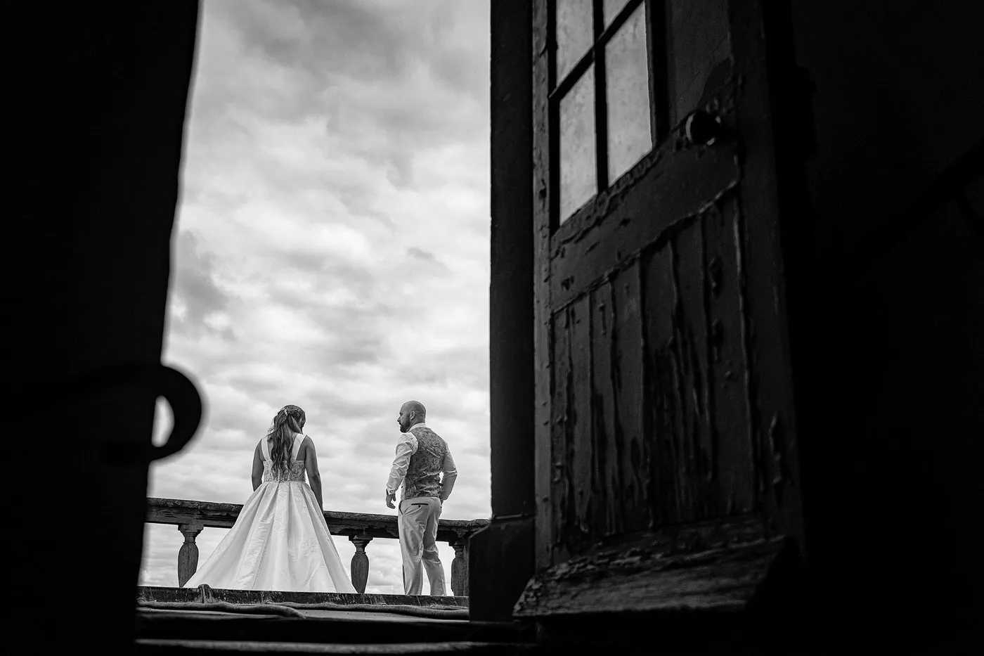 Amy and Andy on the roof of Wollaton Hall, framed through an ancient doorway against a clouded sky