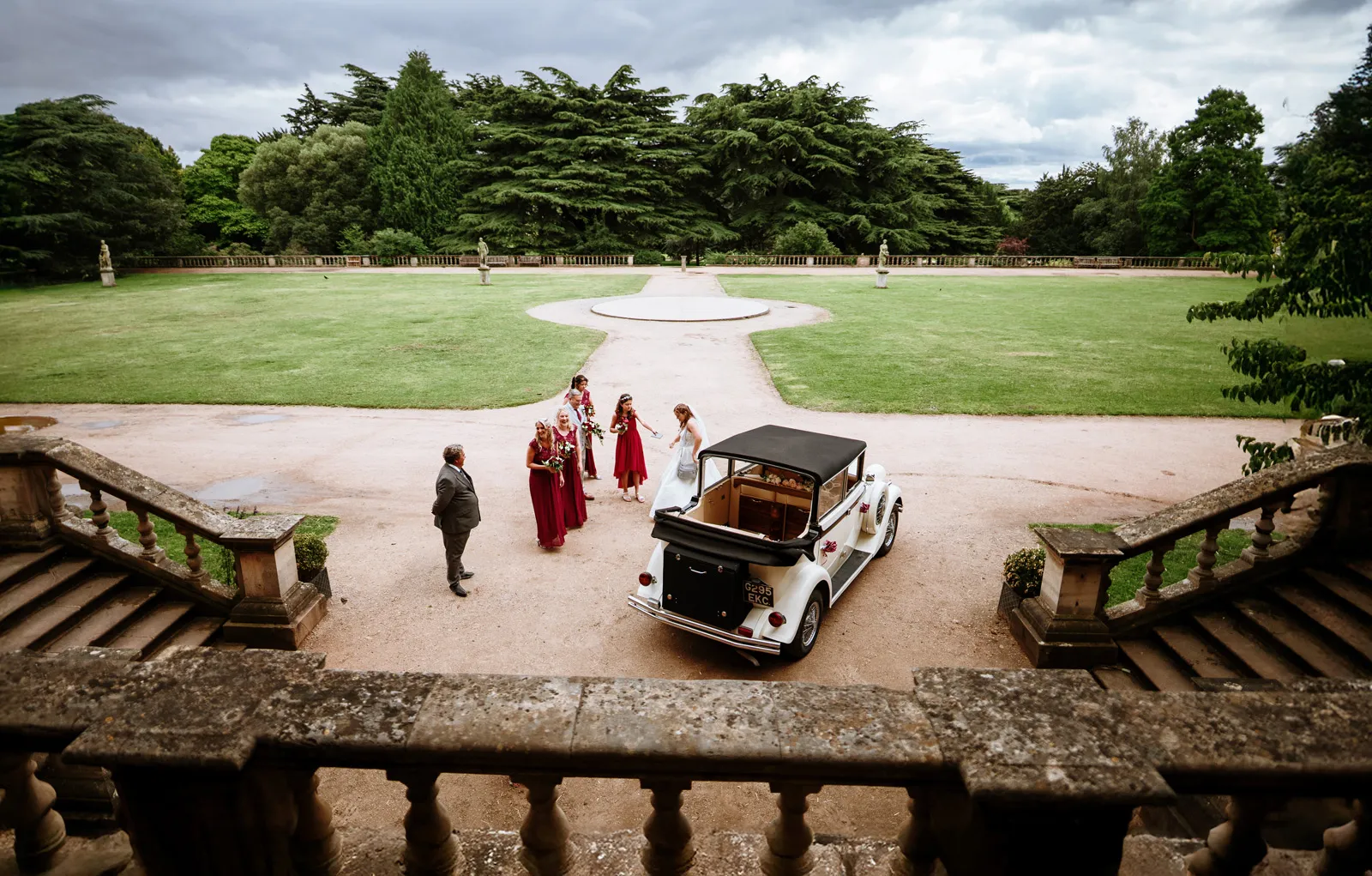 Looking down from the steps of Wollaton Hall — wedding party arriving, formal gardens beyond